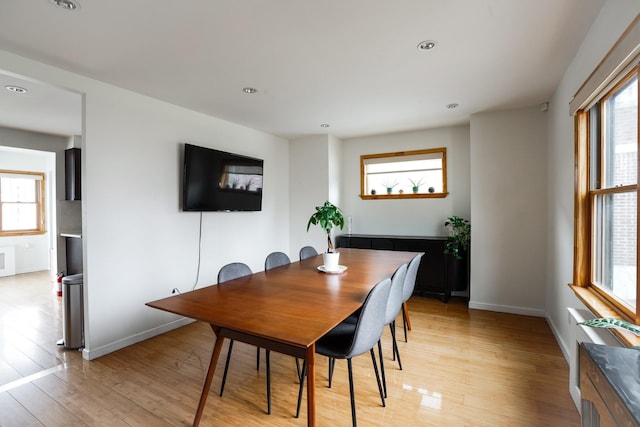 dining room with light wood-type flooring, baseboards, and a healthy amount of sunlight