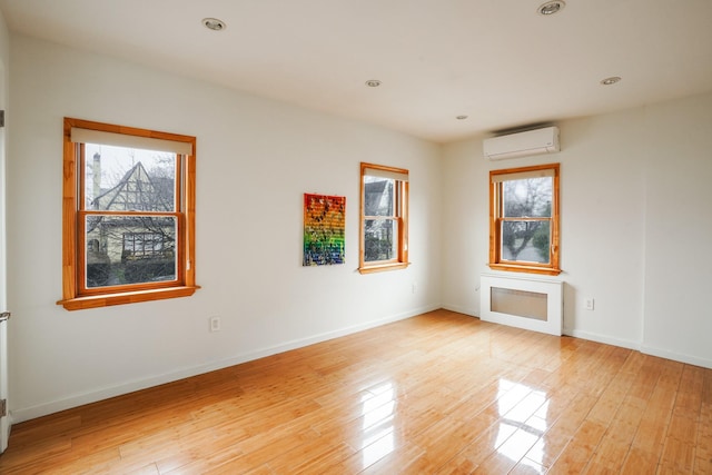 spare room featuring an AC wall unit, recessed lighting, baseboards, and light wood finished floors