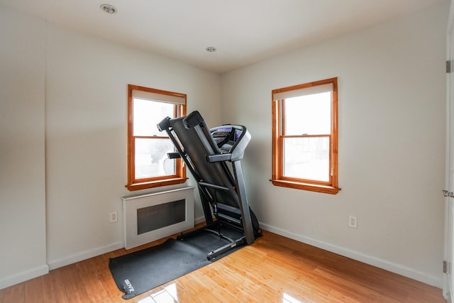 workout area with hardwood / wood-style flooring, heating unit, and baseboards