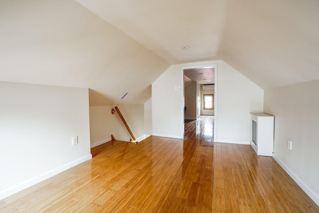 bonus room featuring baseboards, light wood-style floors, and vaulted ceiling