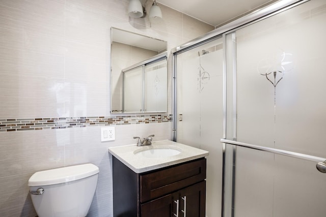 bathroom with vanity, tile walls, toilet, and tiled shower