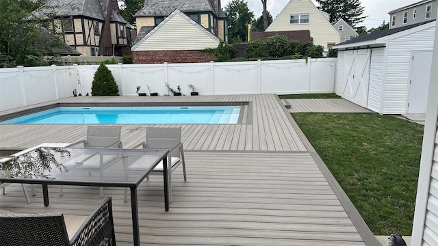 view of pool with a wooden deck, an outdoor structure, a fenced in pool, and a fenced backyard