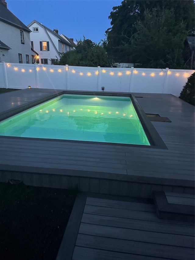 view of swimming pool featuring a deck and a fenced backyard