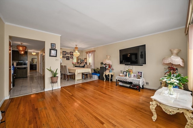 living area with a chandelier, ornamental molding, and hardwood / wood-style floors