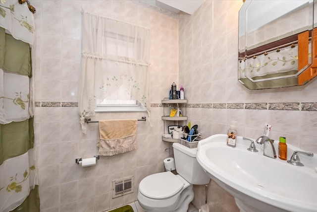 full bathroom with visible vents, toilet, tile walls, and a sink