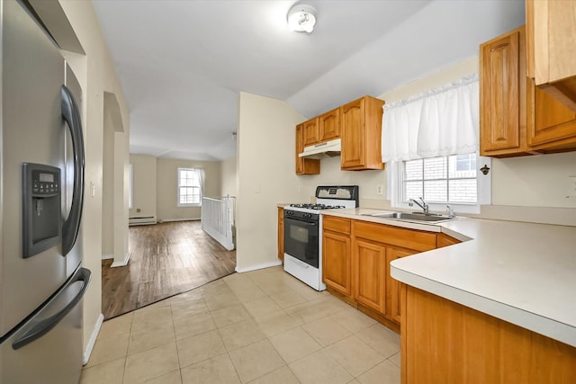 kitchen featuring stainless steel refrigerator with ice dispenser, a sink, under cabinet range hood, lofted ceiling, and white gas range