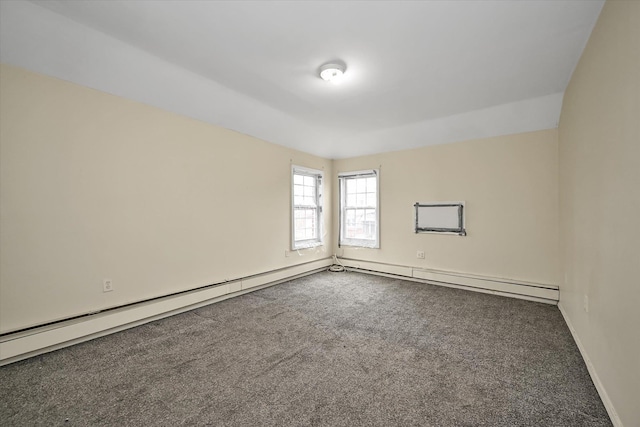 carpeted spare room featuring a baseboard heating unit and baseboards