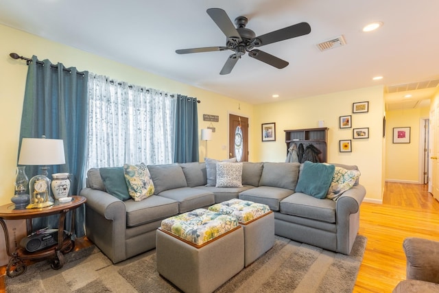 living area featuring visible vents, light wood finished floors, baseboards, attic access, and recessed lighting