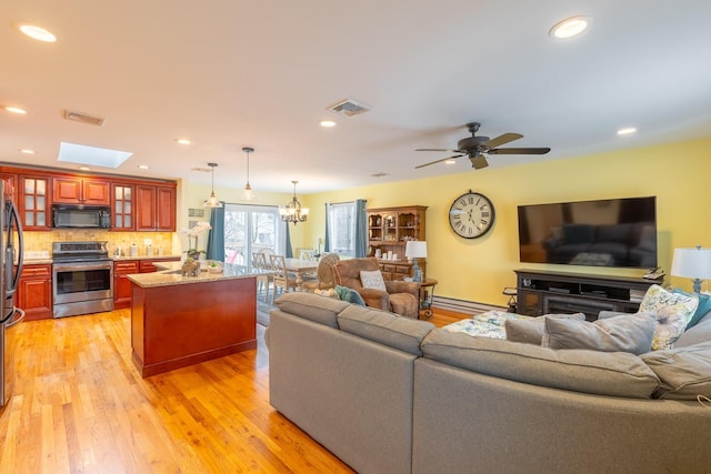 living area with ceiling fan with notable chandelier, recessed lighting, light wood-style floors, and visible vents