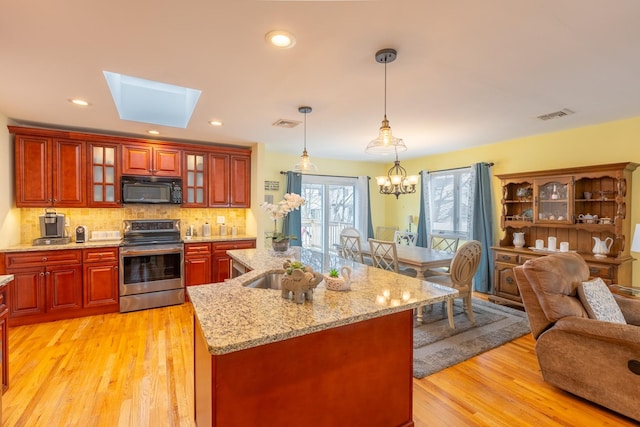 kitchen with visible vents, backsplash, black microwave, open floor plan, and stainless steel electric range oven