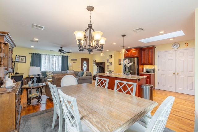 dining room featuring a skylight, recessed lighting, visible vents, and light wood finished floors