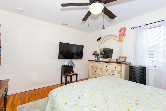 bedroom featuring visible vents, a ceiling fan, baseboards, and wood finished floors