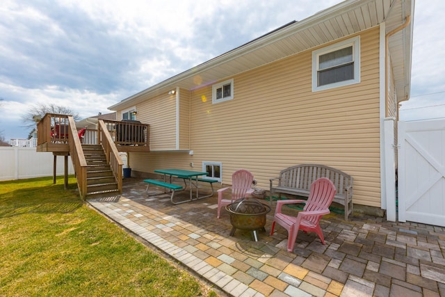 view of patio with stairs, a deck, fence, and an outdoor fire pit