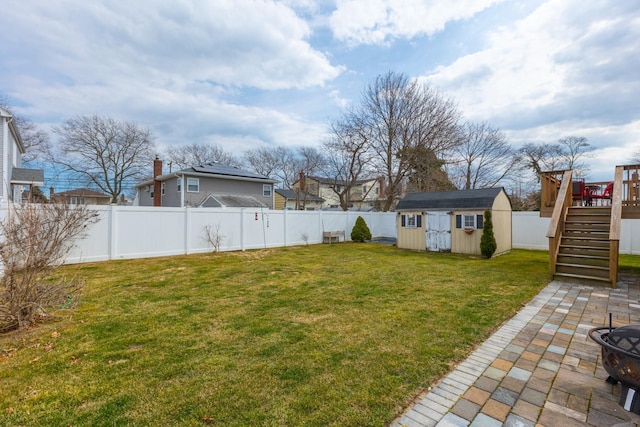 view of yard with stairway, an outdoor structure, a fenced backyard, a storage unit, and a patio