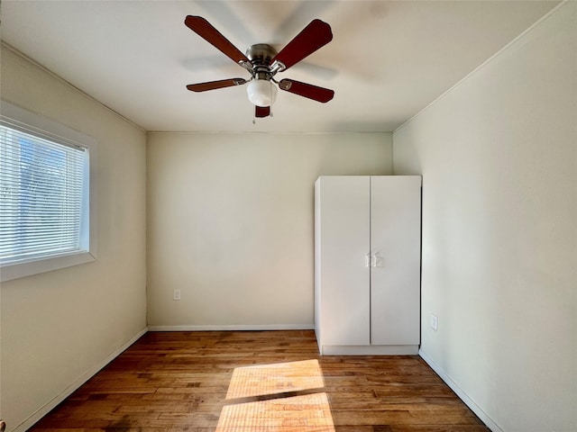 empty room with wood finished floors, baseboards, and ceiling fan