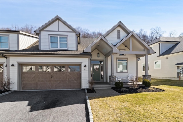 view of front of home with aphalt driveway, an attached garage, roof with shingles, and a front lawn