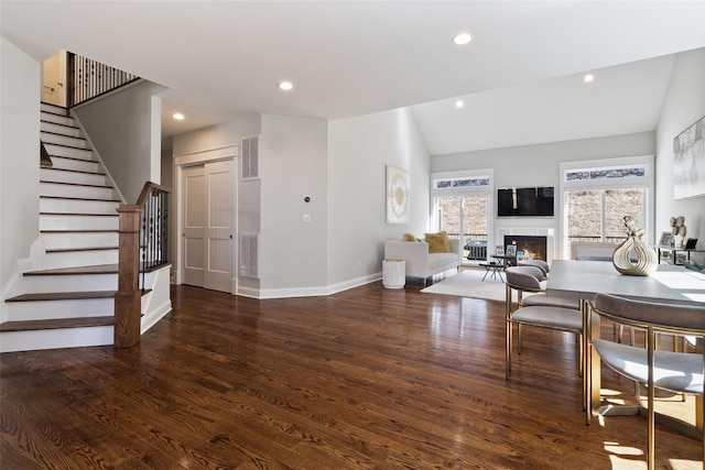 living room featuring visible vents, stairway, a lit fireplace, and wood finished floors