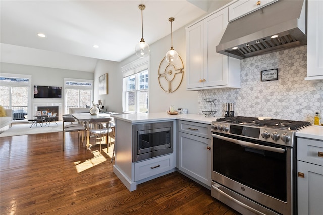 kitchen featuring a peninsula, gray cabinets, appliances with stainless steel finishes, exhaust hood, and open floor plan