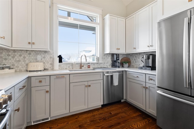 kitchen featuring dark wood-style floors, gray cabinetry, a sink, appliances with stainless steel finishes, and tasteful backsplash