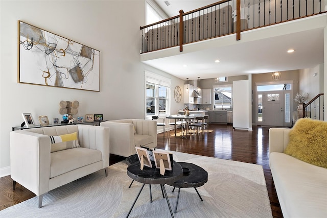 living room featuring baseboards, dark wood finished floors, stairway, recessed lighting, and a towering ceiling