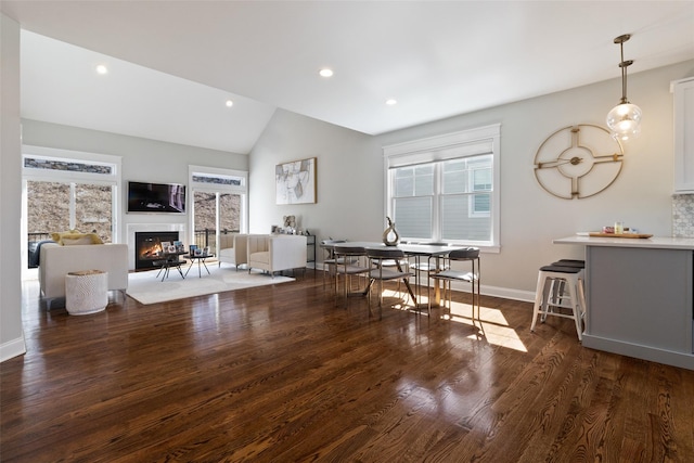 dining room with recessed lighting, wood finished floors, a glass covered fireplace, and vaulted ceiling