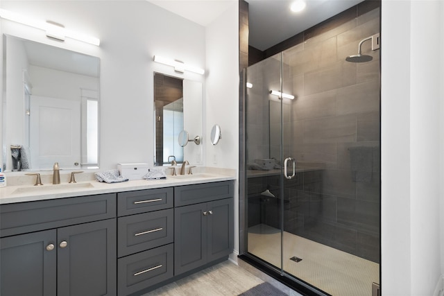 bathroom featuring a sink, double vanity, wood finished floors, and a shower stall