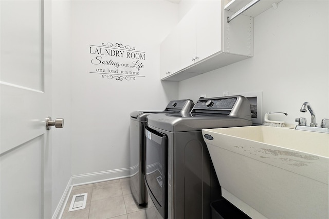 clothes washing area with light tile patterned floors, baseboards, washing machine and clothes dryer, cabinet space, and a sink