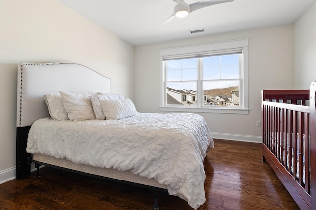 bedroom featuring a ceiling fan, wood finished floors, visible vents, and baseboards