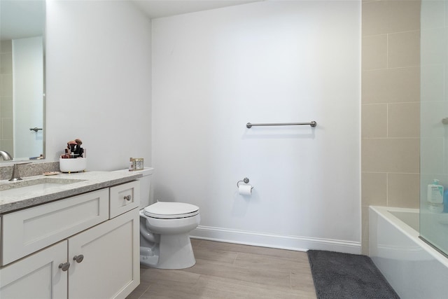 bathroom with toilet, vanity, baseboards, and wood finished floors