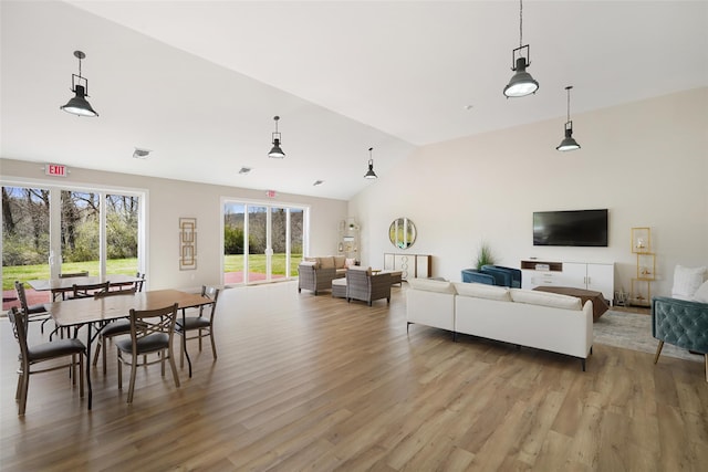 living room with light wood-type flooring, lofted ceiling, and visible vents