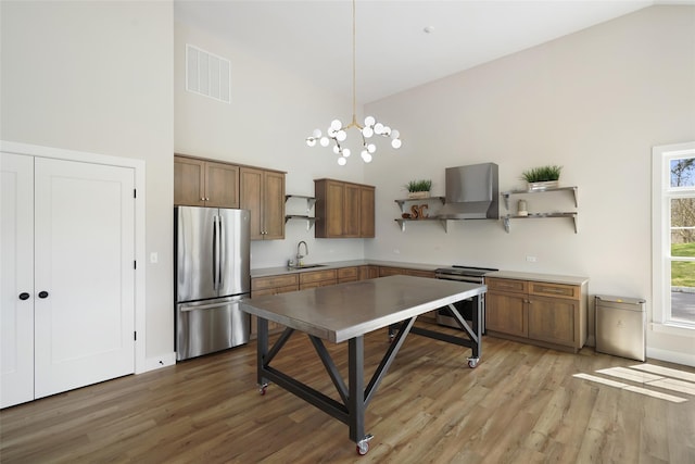 kitchen with visible vents, open shelves, a sink, stainless steel appliances, and wall chimney exhaust hood