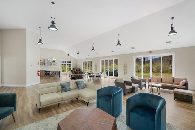 living area with lofted ceiling, baseboards, visible vents, and light wood-type flooring