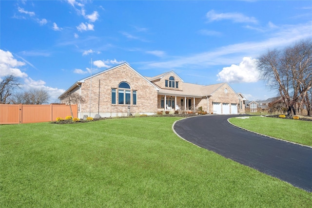 view of front of house featuring a front yard, brick siding, driveway, and fence