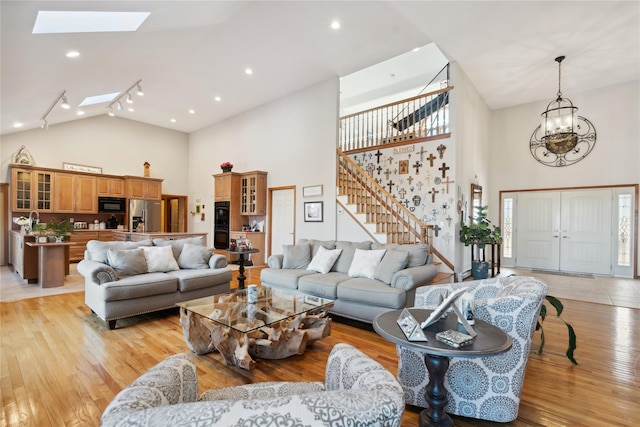 living area featuring a chandelier, light wood-type flooring, a skylight, and stairs