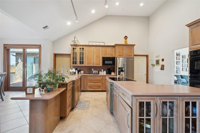 kitchen with visible vents, a center island, glass insert cabinets, black appliances, and a sink