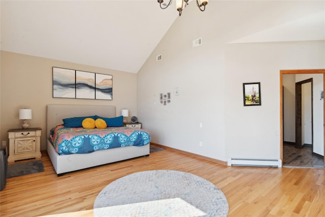 bedroom with a baseboard heating unit, wood finished floors, visible vents, and a chandelier