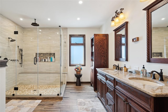 bathroom featuring double vanity, a shower stall, baseboards, and a sink