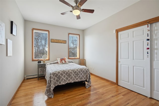 bedroom featuring baseboards, light wood-type flooring, and a baseboard radiator