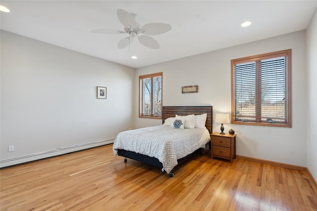 bedroom with a baseboard radiator, baseboards, multiple windows, and light wood finished floors