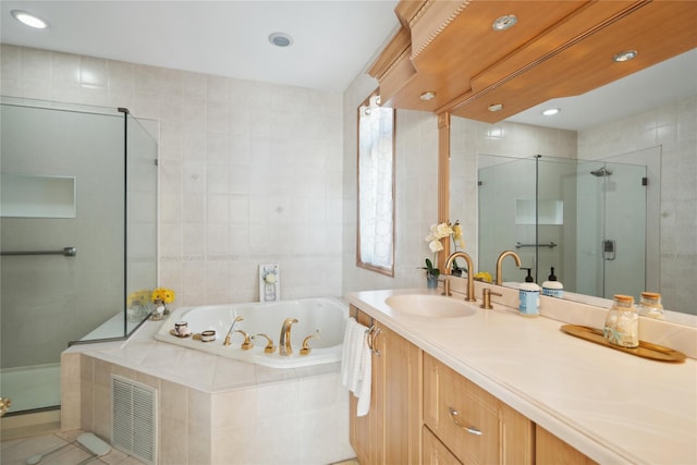 full bathroom with visible vents, vanity, a whirlpool tub, a stall shower, and tile walls