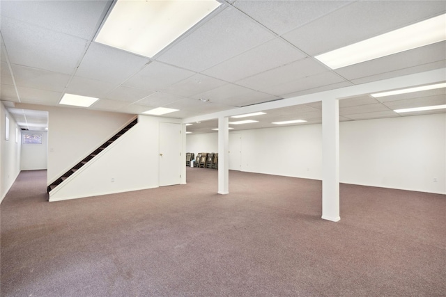 finished below grade area featuring stairway, carpet, and a paneled ceiling