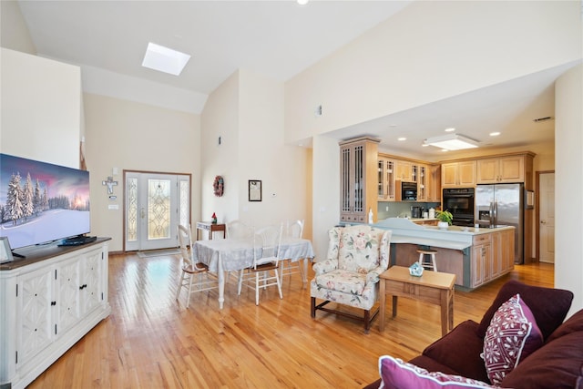 living area with high vaulted ceiling, recessed lighting, a skylight, and light wood-style floors