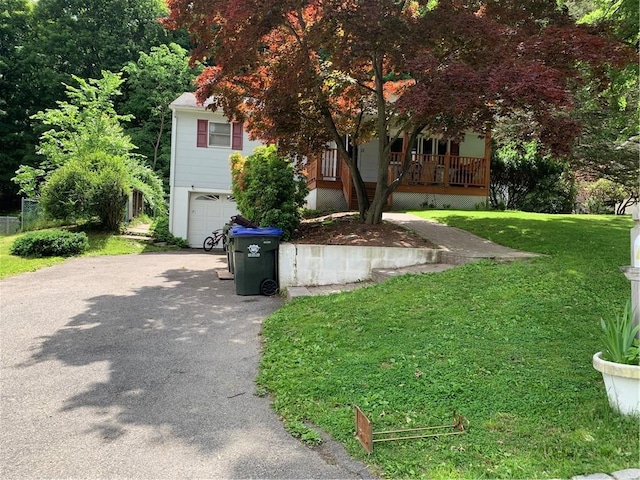 view of front of house with a front lawn, an attached garage, covered porch, and driveway