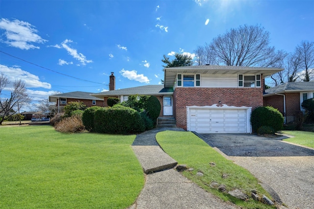 tri-level home with driveway, an attached garage, a chimney, a front lawn, and brick siding