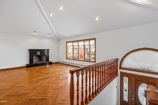 foyer featuring a fireplace with raised hearth, high vaulted ceiling, a baseboard heating unit, and baseboards