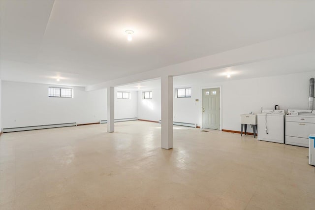 below grade area featuring a baseboard radiator, baseboards, baseboard heating, and washer and clothes dryer