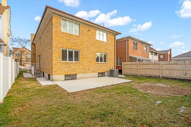 back of property with a patio, a yard, a fenced backyard, central AC, and brick siding