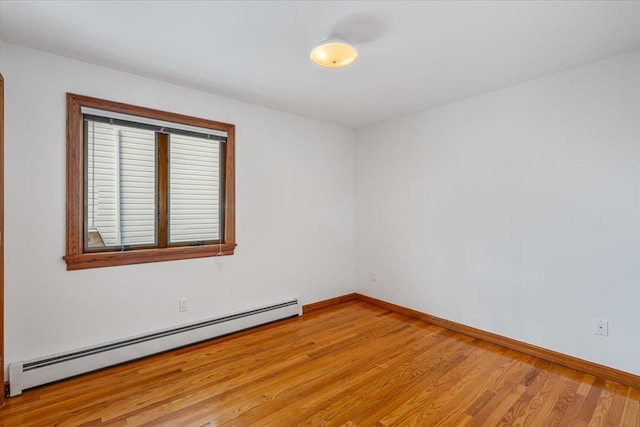 spare room with light wood finished floors, a baseboard heating unit, and baseboards