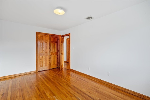 empty room featuring visible vents, baseboards, and wood finished floors