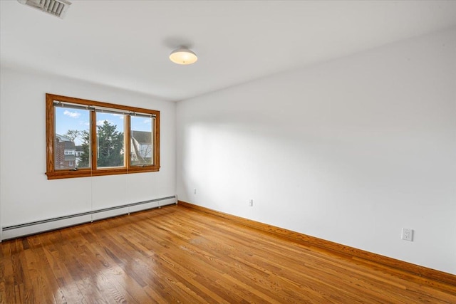 empty room featuring baseboards, wood finished floors, visible vents, and a baseboard radiator